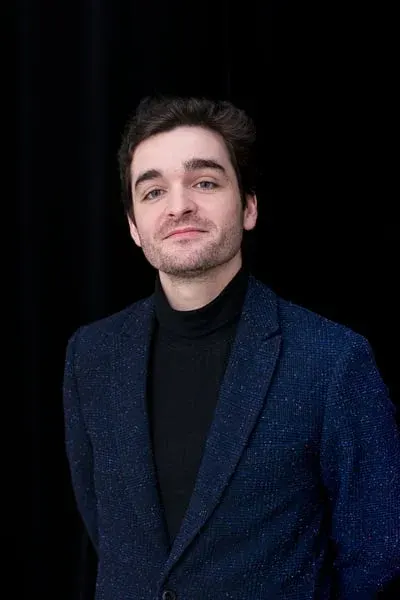 Portrait de Léo Barcet, veste bleu nuit sur fond noir