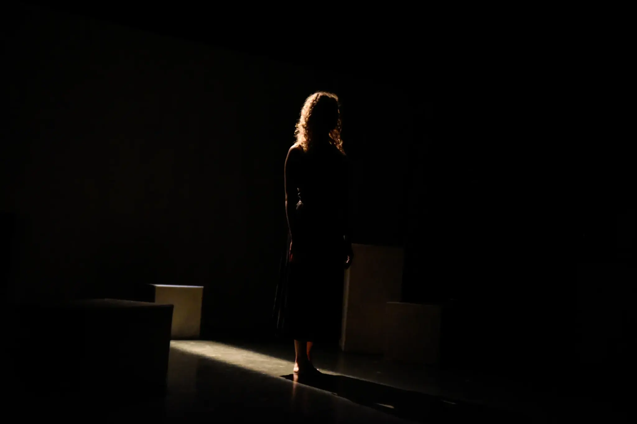 Une silhouette seule sur une scène plongée dans le noir